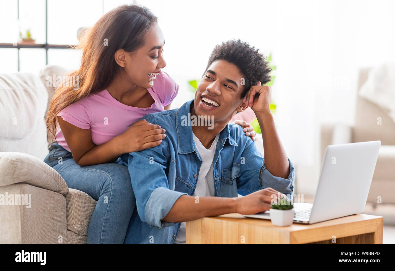 Happy black couple working together on laptop at home. Stock Photo