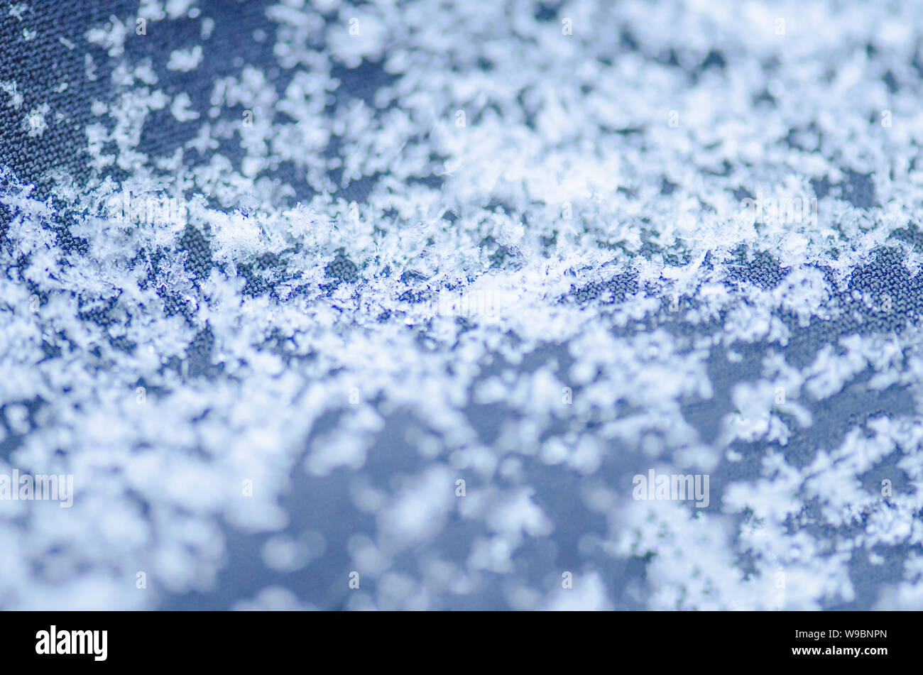 Macro photo of real snow crystal. Snowflake  on blue  background.  Fashion background with white snowflakes Stock Photo
