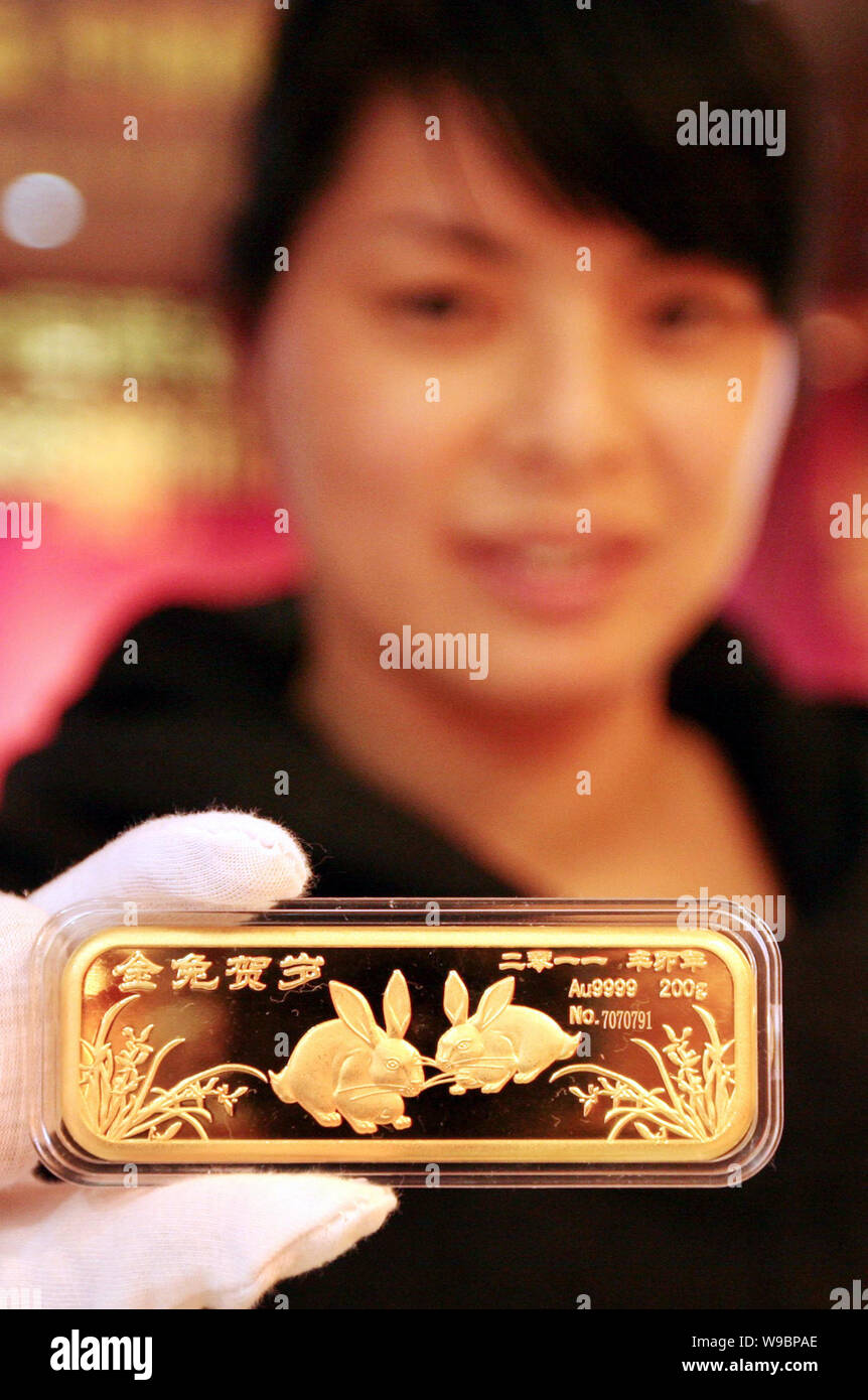 A Chinese staff shows a gold bar marking the Year of the Rabbit at a gold shop in Zhoushan city