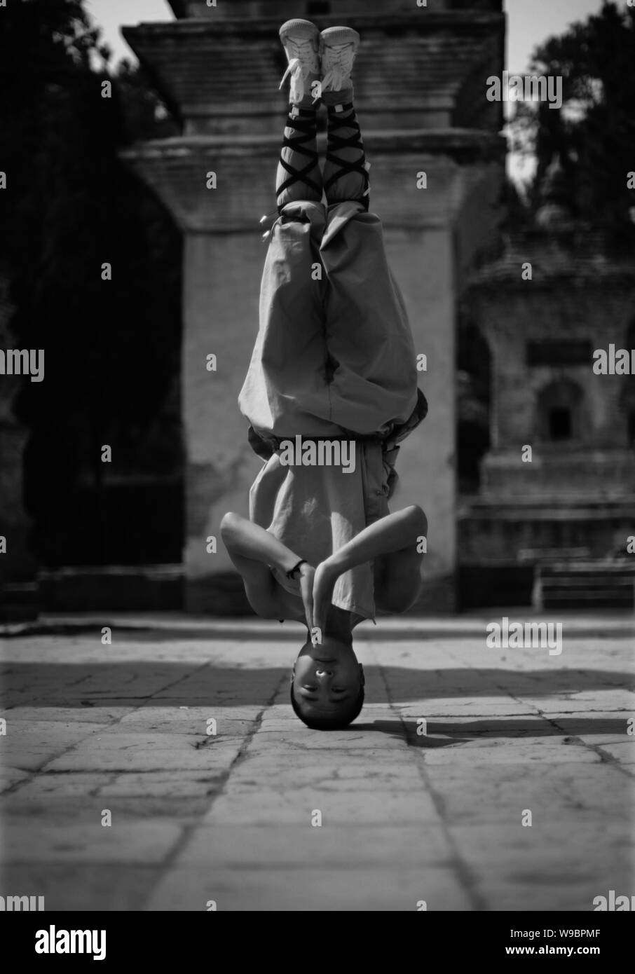 A young Shaolin monk performs headstand while practising kungfu at the Shaolin Temple in Dengfeng city, central Chinas Henan province, 15 August 2009. Stock Photo