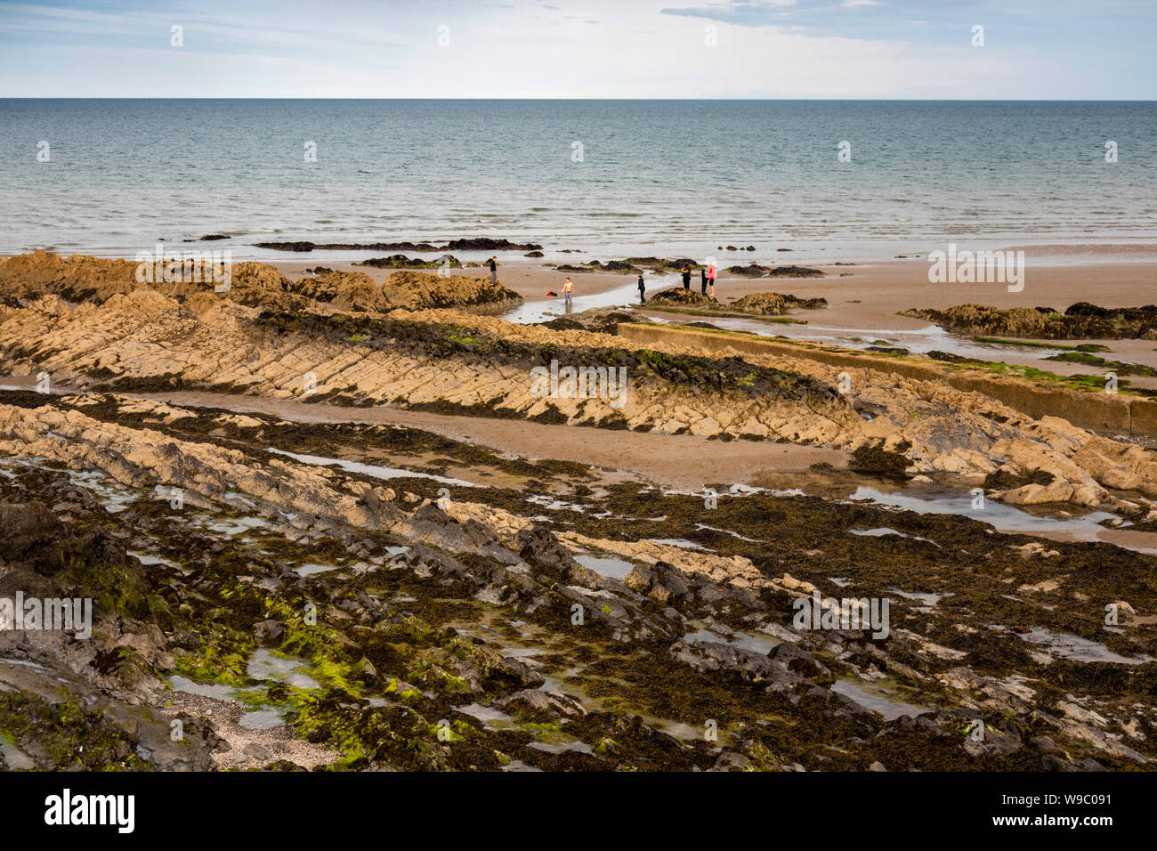 Ireland, Leinster, Fingal, Portmarnock, children playing on rocky shore exposed at low tide Stock Photo