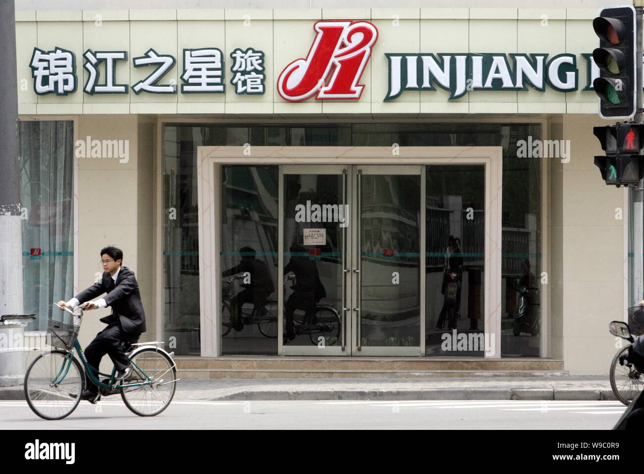 --FILE--Chinese cyclists ride past a branch of Jinjiang Inn in Shanghai, China, 7 April 2008.   Jinjiang Inn Budget Hotels, a subsidiary of Shanghai J Stock Photo