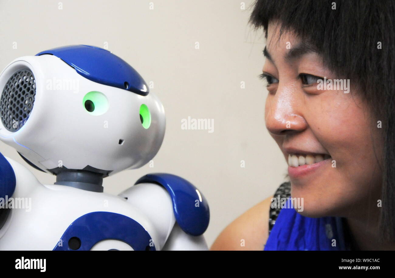A woman looks at a Nao, the humanoide robot made by Aldebaran Robotics, at Harbin Institute of Technology in Harbin city, northeast Chinas Heilongjian Stock Photo