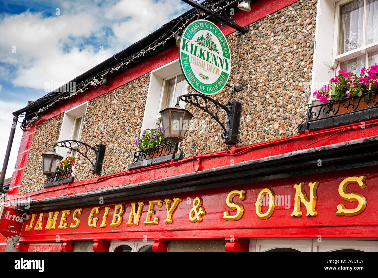 Ireland, Co Dublin, Malahide, New Street, James Gibney’s traditional Irish pub sign hanging basket and Kilkenny beer advertising Stock Photo