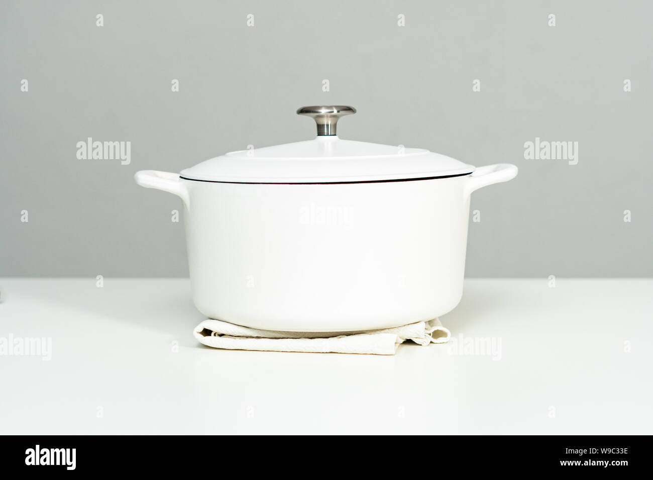 White enameled cast iron covered round dutch oven on a whjite background. Stock Photo