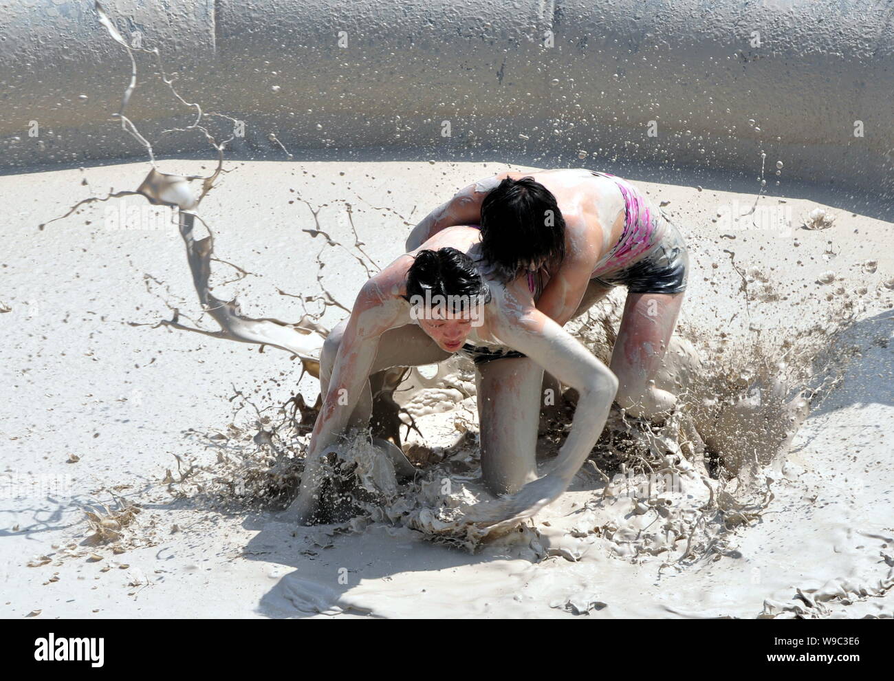Two Chinese women wrestle in a mud pool during an interntional womens mud wrestling contest along the East Lake in Wuhan city, central Chinas Hubei pr Stock Photo