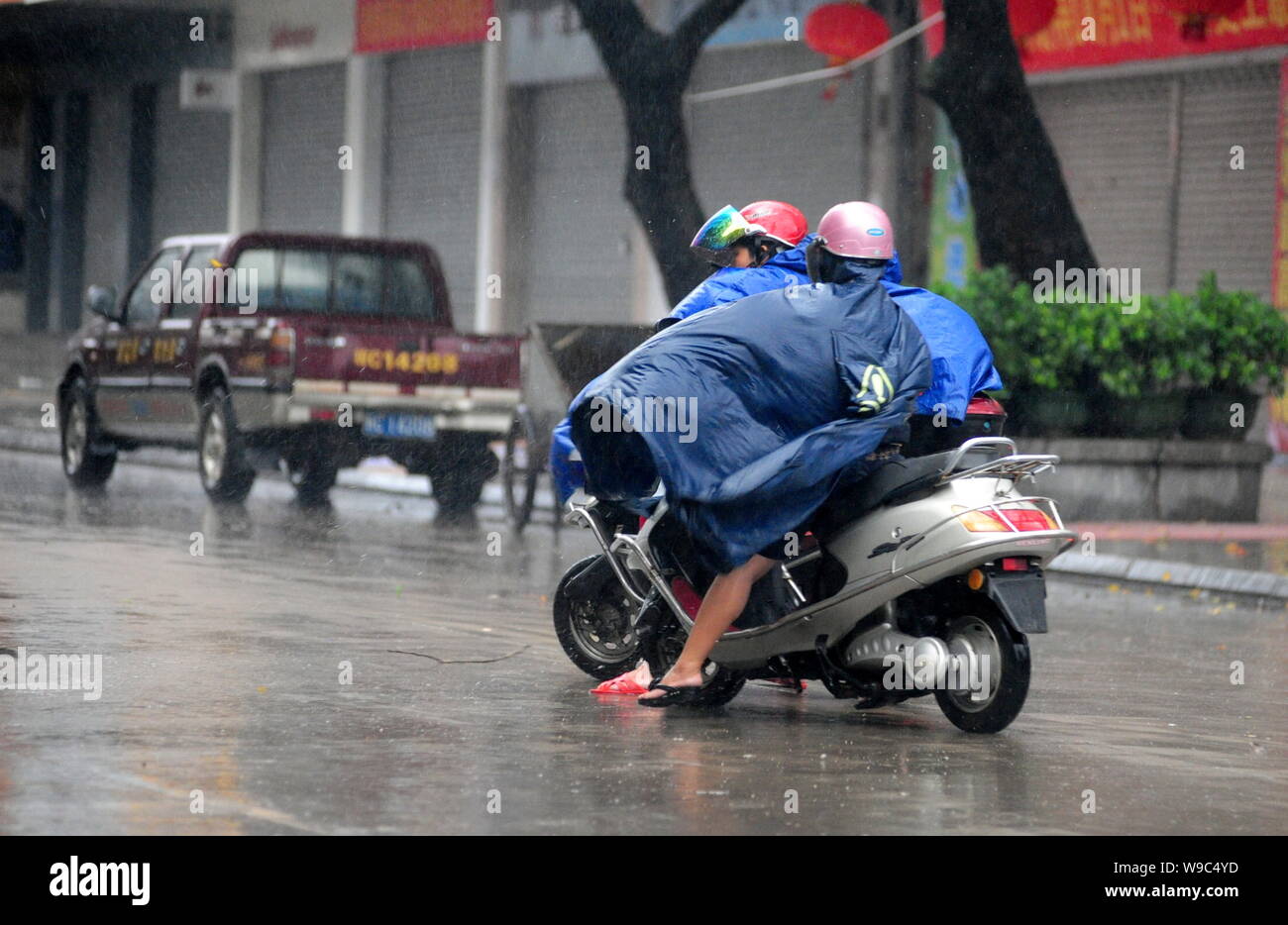 Chinese cyclists ride their motor scooters in heavy rain and strong winds caused by Typhoon Parma in Qionghai city, south Chinas Hainan province, Mond Stock Photo