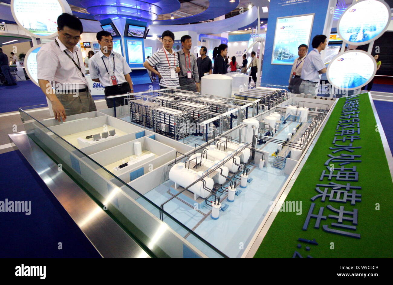 Visitors look at a model water treatment system on display at the 12th