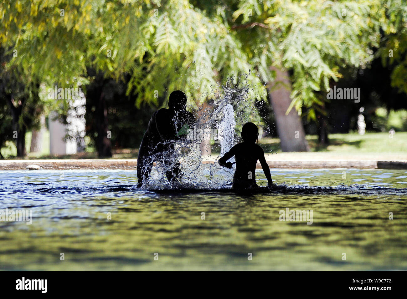 A man and her daughter finding relief in a fountain of Turia's Garden in Valencia, during a heatwave. Stock Photo