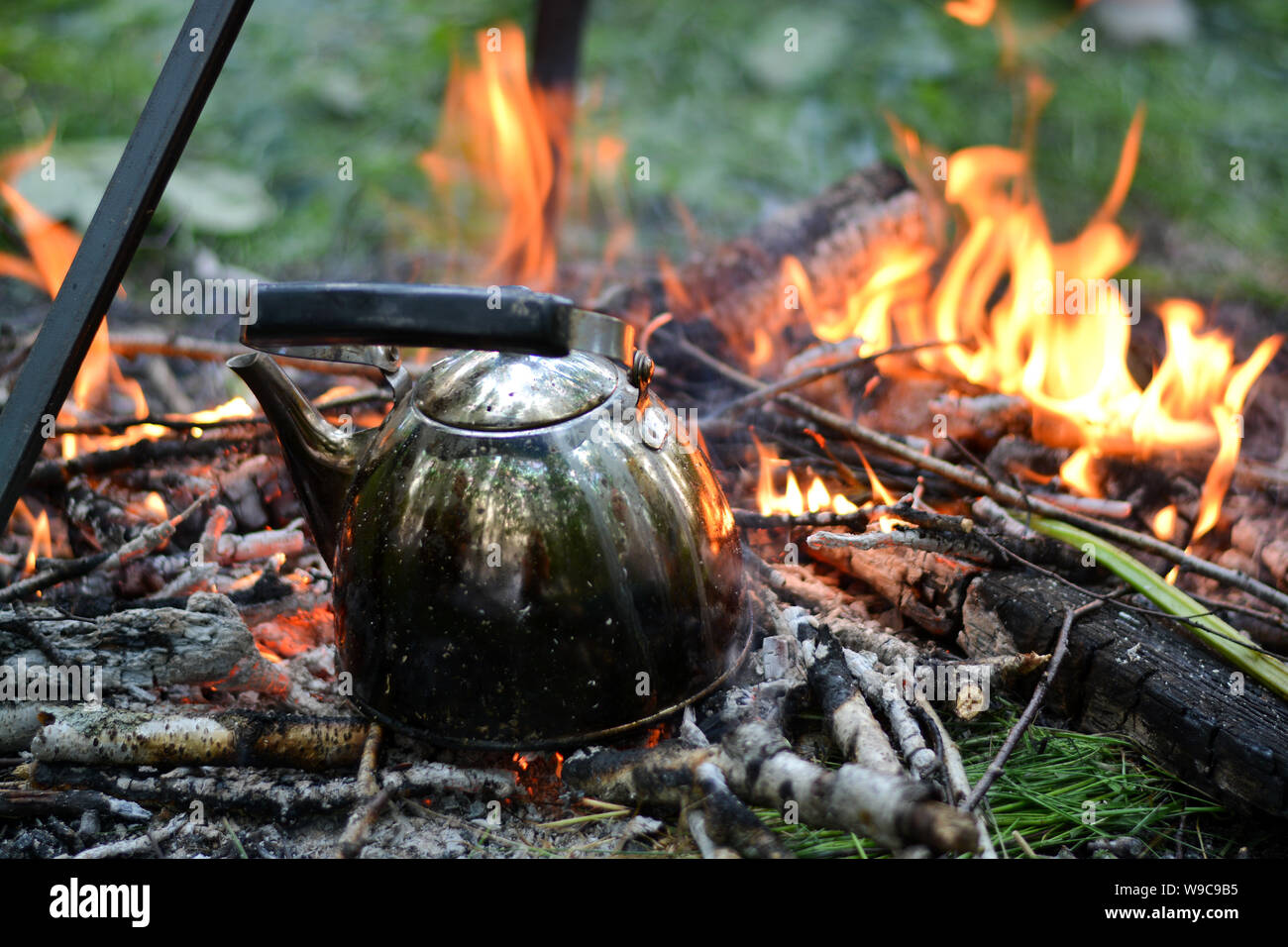 old shiny metal kettle basks on a fire, travel vacation weekend on a summer day, horizontal photo Stock Photo