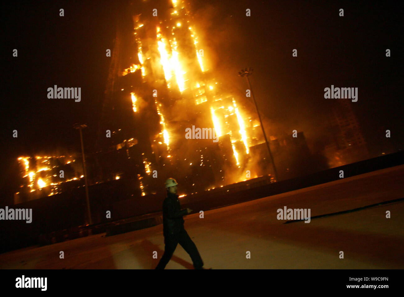 A man walks past the Mandarin Oriental Hotel building seen on fire near the new CCTV Tower during the Lantern Festival in Beijing, China, Monday, 9 Fe Stock Photo
