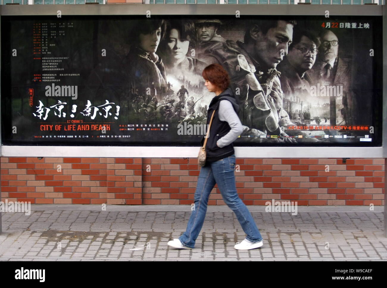 --FILE--A Chinese woman walks past a poster for the movie City of Life and Death, directed by Chinese film director Lu Chuan, in Shanghai, China, 14 A Stock Photo