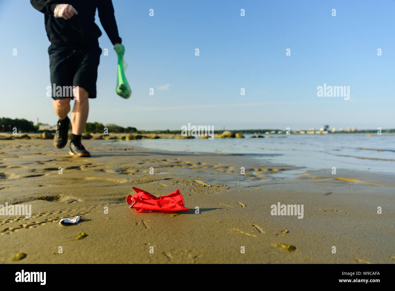 Man picking garbage on beach. At jogging or running. Plogging concept ...