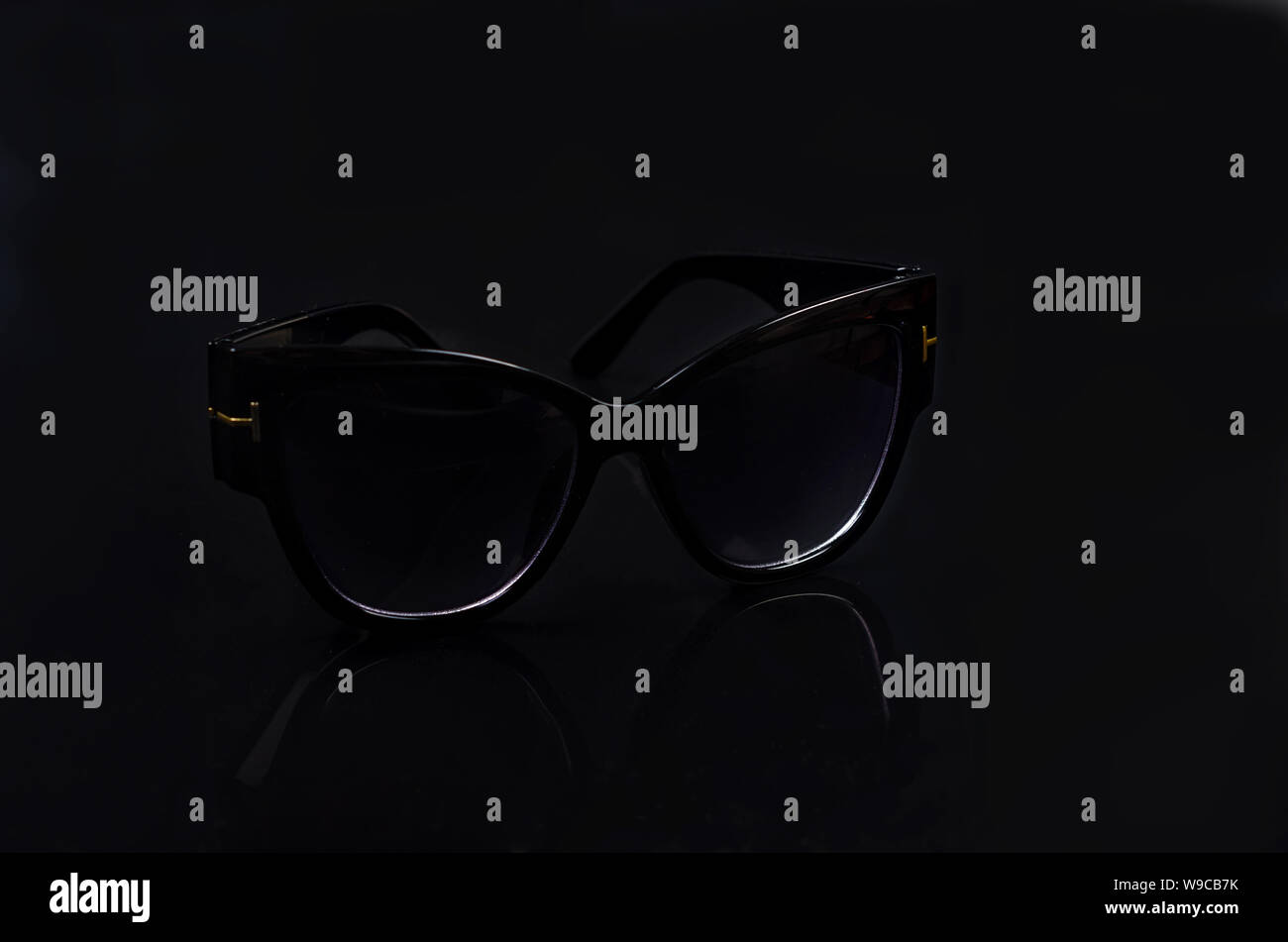 black sunglasses with reflection on black glossy background, copy space