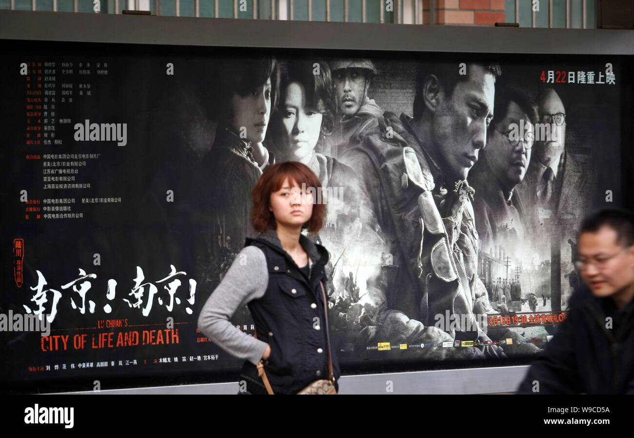 --FILE--Local Chinese citizens pass by a poster for the movie City of Life and Death, directed by Chinese film director Lu Chuan, in Shanghai, China, Stock Photo