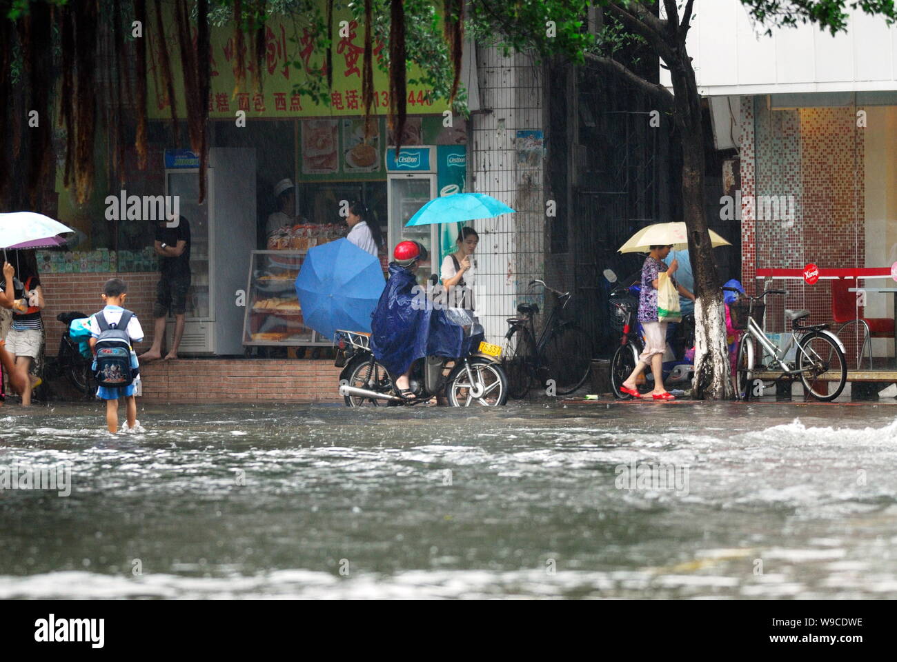 Local Chinese citizens walk on a flooded street after heavy rain caused by Tropical Storm Parma in Haikou city, south Chinas Hainan province, Monday, Stock Photo