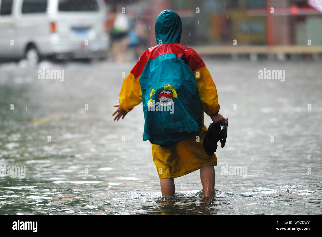 A Chinese student walks on a flooded street after heavy rain caused by Tropical Storm Parma in Haikou city, south Chinas Hainan province, Monday, 12 O Stock Photo