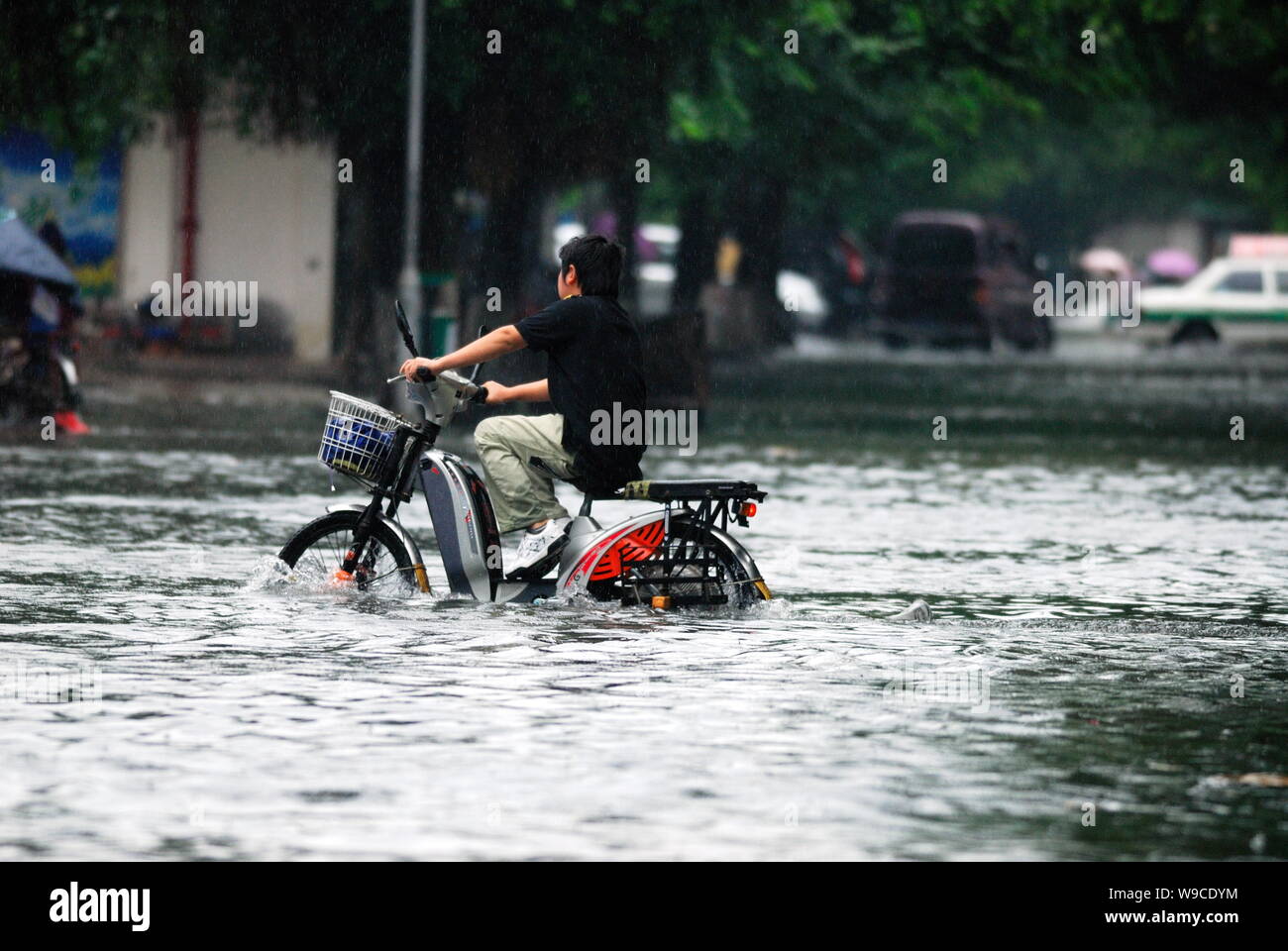 A Chinese cyclist rides his bicycle through a flooded street after heavy rain caused by Tropical Storm Parma in Haikou city, south Chinas Hainan provi Stock Photo