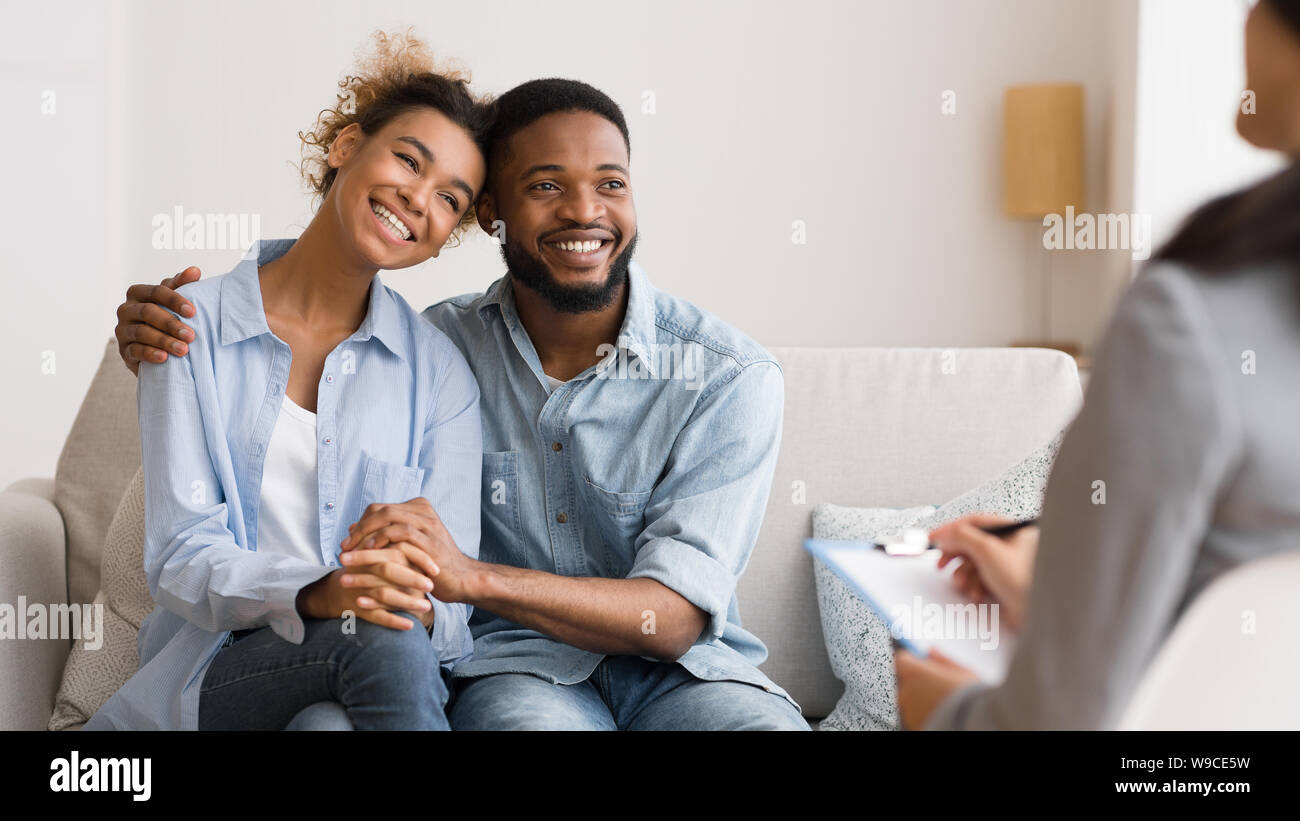 Positive African American Couple Hugging After Reconciling At Psychologist's Office Stock Photo