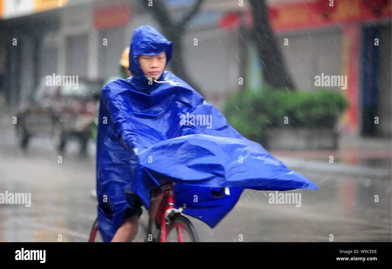 A Chinese cyclist rides her bicycle in heavy rain and strong winds caused by Typhoon Parma in Qionghai city, south Chinas Hainan province, Monday, 12 Stock Photo