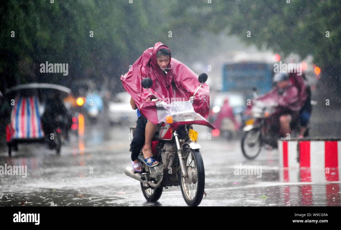 A Chinese man rides his motorcycle through heavy rain and strong winds caused by Typhoon Parma in Qionghai city, south Chinas Hainan province, Monday, Stock Photo