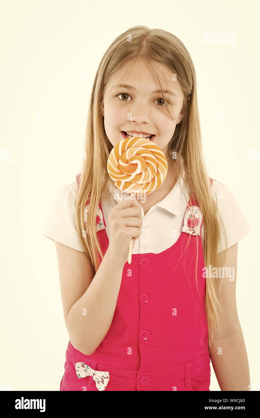 Girl eat lollipop isolated on white. Little child enjoy candy on stick