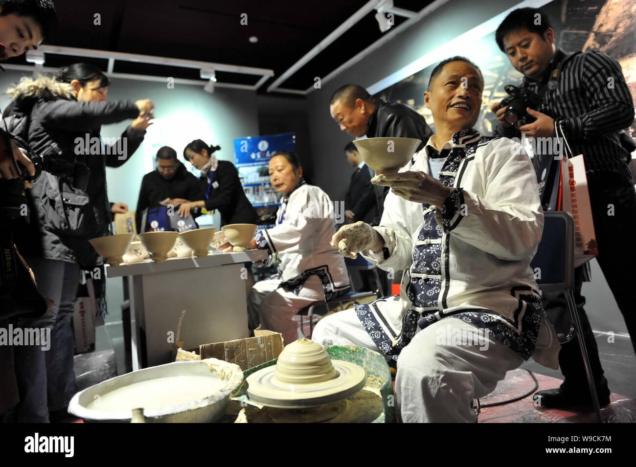 Chinese visitors look at two craftspersons making porcelain wares at a porcelain show in Beijing, China, 30 November 2009.   Six hundred of the finest Stock Photo