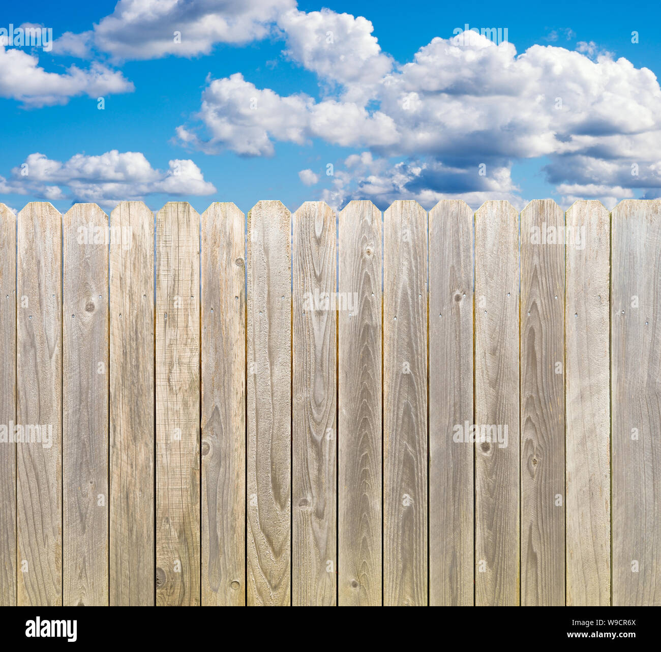 Whitewashed rustic wood privacy fence with blue sky and clouds Stock
