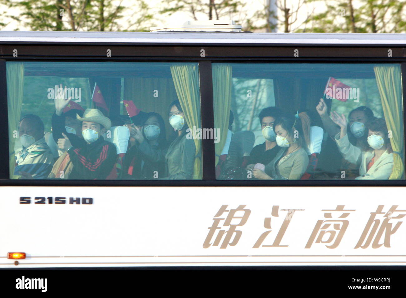 Masked Chinese passengers flying back from Mexico wave in a bus when leaving the Shanghai Pudong International Airport for a hotel nearby to be quaran Stock Photo