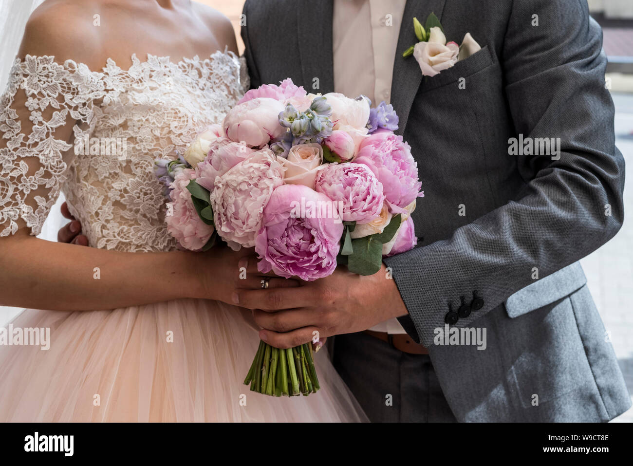 Wedding. Wedding bouquet of pink and lilac peonies in bride's and groom's hands Stock Photo