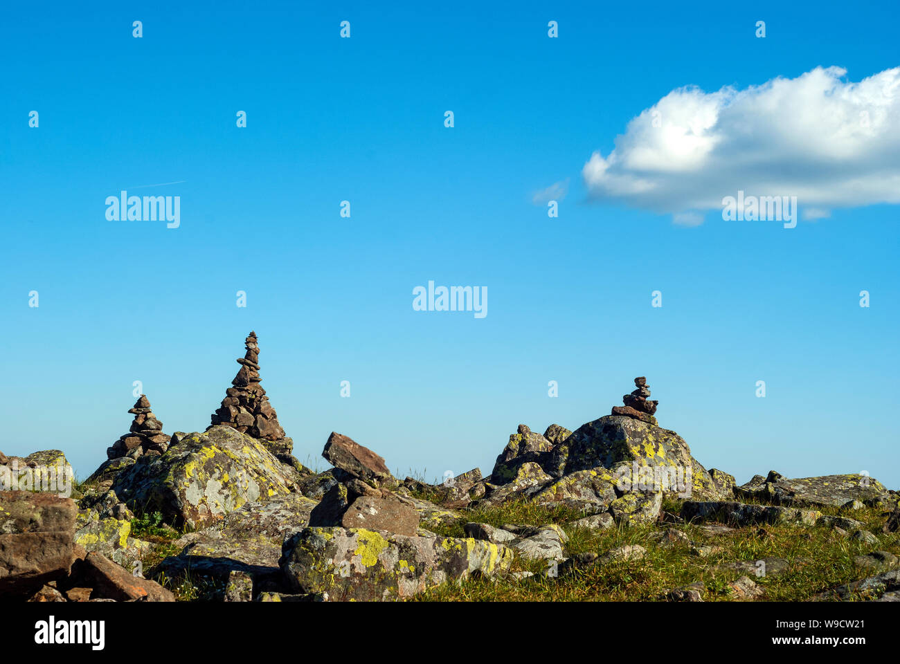 bright landscape of a high-altitude plateau with folded travelers pyramids cairns of stones under a blue sky with clouds Stock Photo
