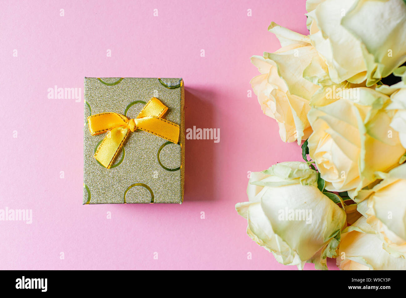 Gift box and white roses on pink table from above, flat lay frame Stock ...