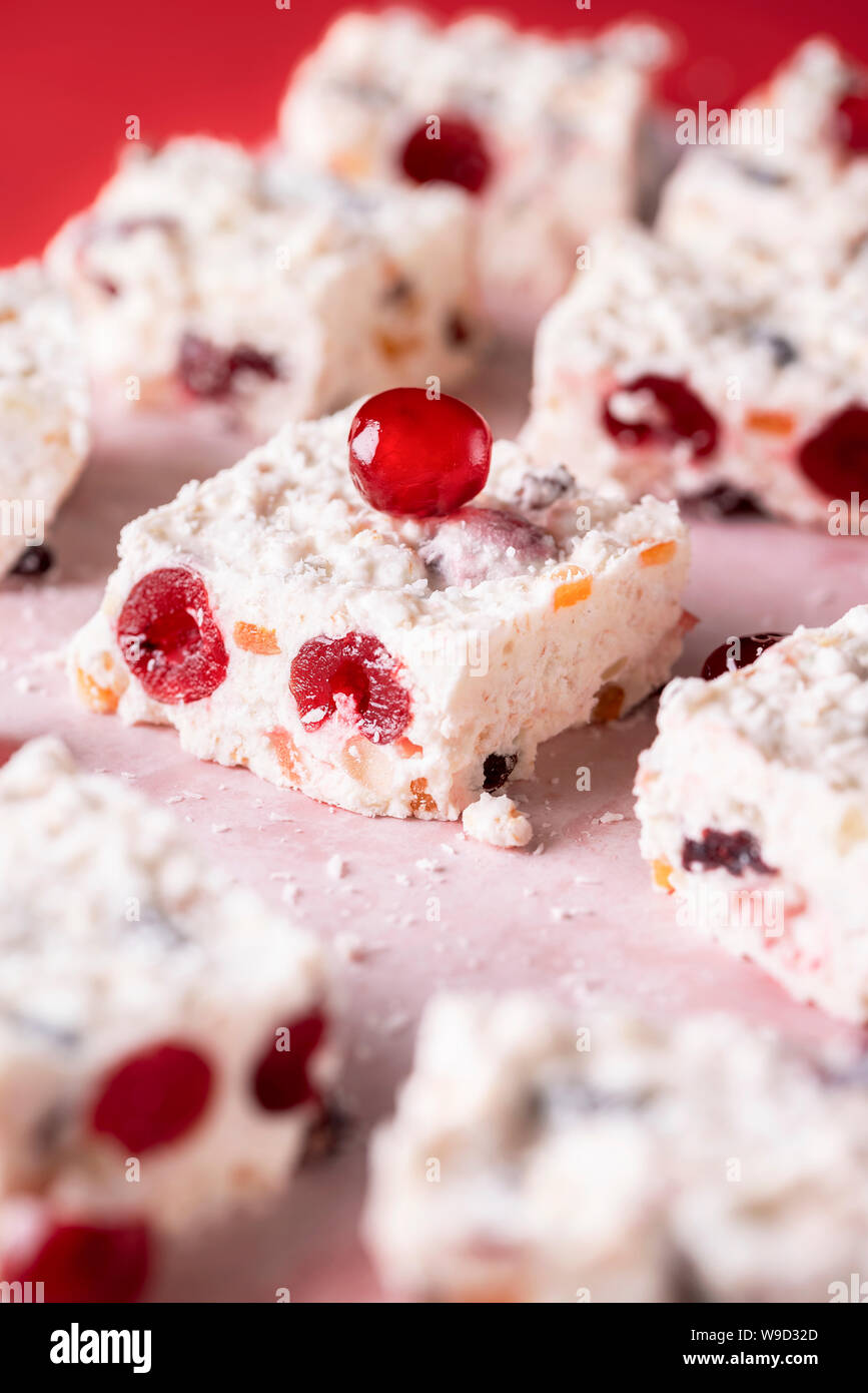 Australian traditional Xmas dessert with coconut and dried cherries.  Close-up with the white Christmas cake on baking paper. Tasty fruit cake  Stock Photo - Alamy