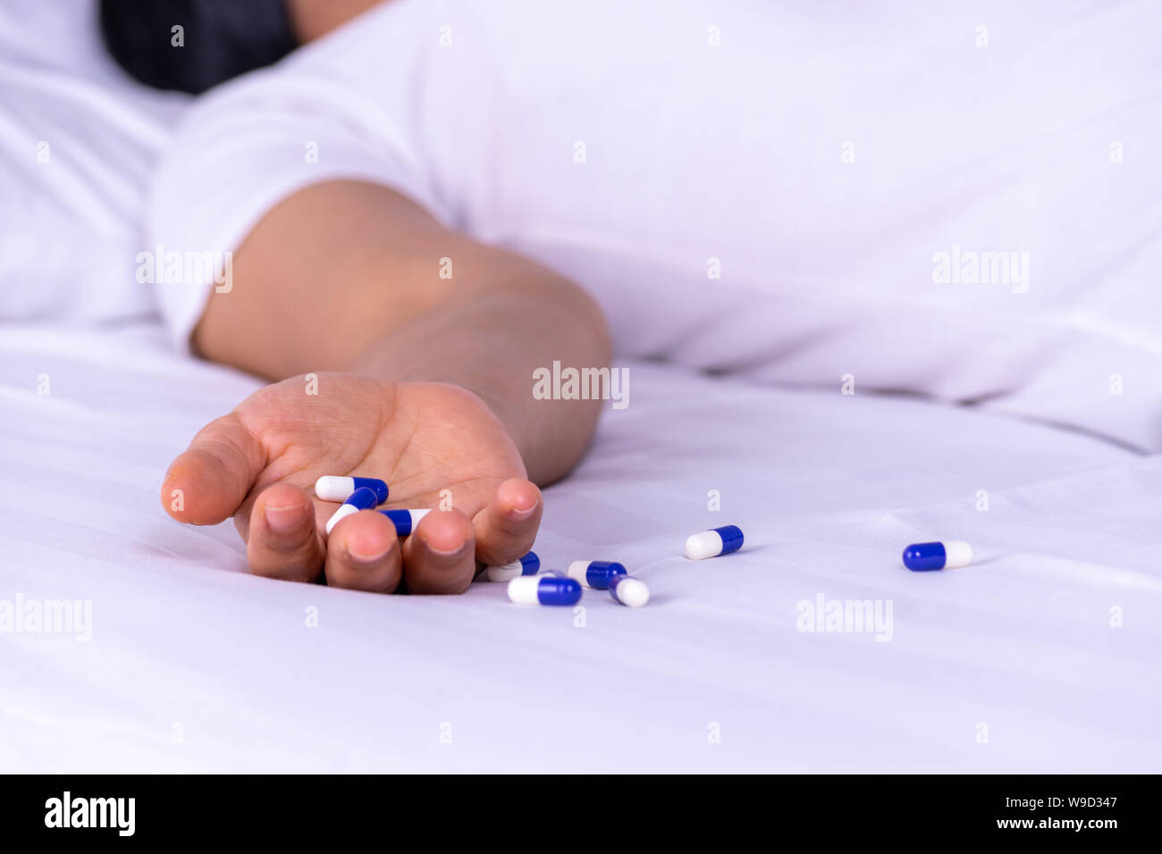 Woman lying on the bed after an overdose of pills at home. Overdose and suicide concept. Stock Photo