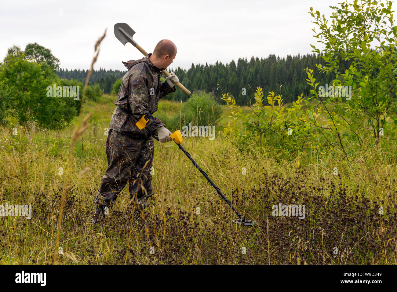 treasure hunter with a shovel and metal detector in a natural landscape ...