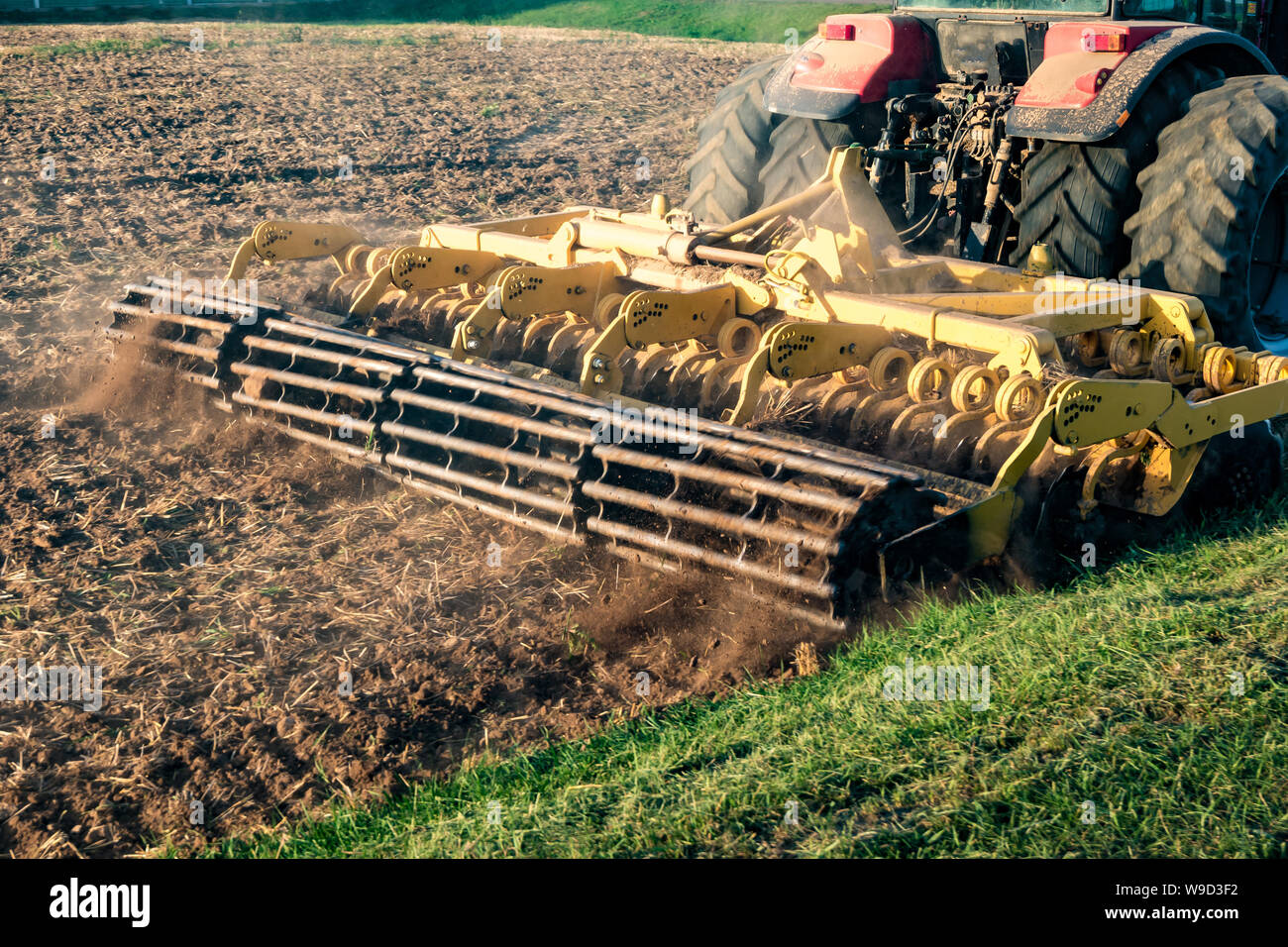 tractor cultivator plows the land, prepares for crops. dust on field Stock Photo