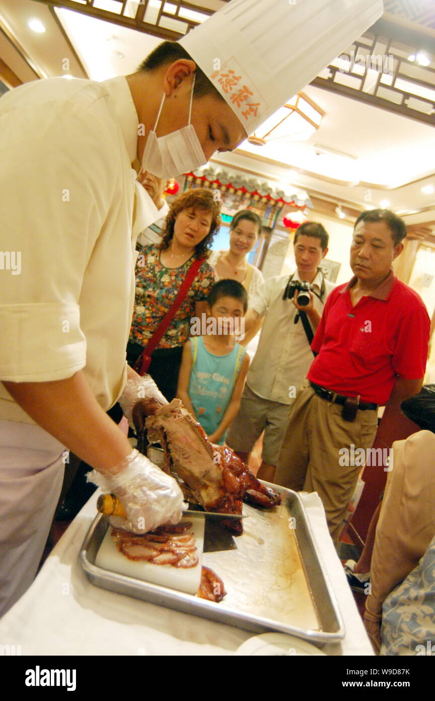 --FILE--A Chinese cook slice a roast duck at a Quanjude roast duck