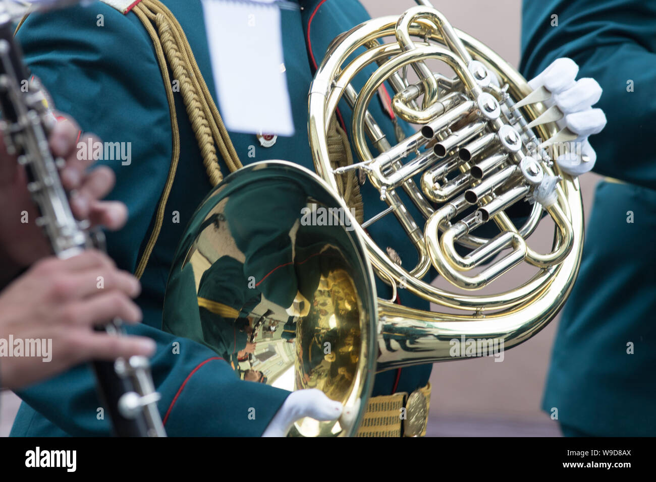 A wind instrument parade - a man in green costume playing french horn Stock Photo