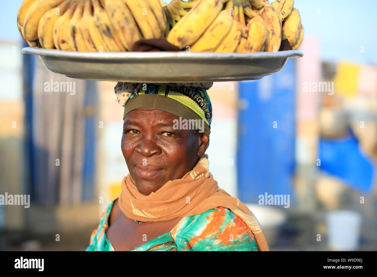 Market woman carries a plate with bananas on her head in Accra, Ghana Stock Photo