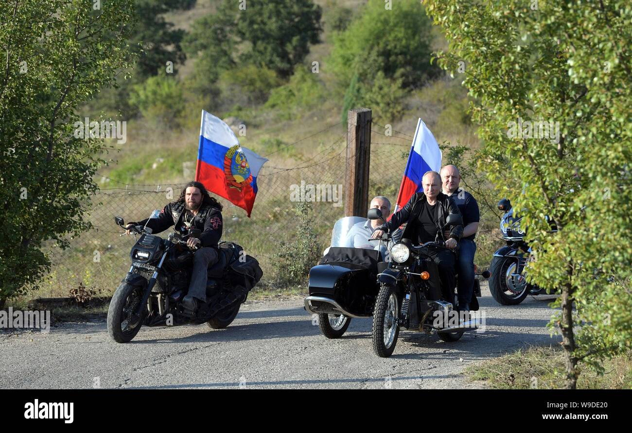 Russian President Vladimir Putin, right, rides a motorcycle alongside the Night Wolves biker gang leader Alexander ‘The Surgeon’ Zaldastanov, left, on their way to the Babylon Shadow bike show and camp August 10, 2019 near Sevastopol, Crimea, Russia. Riding behind Putin in pillion on the motorcycle is Acting Governor of Sevastopol Mikhail Razvozhayev and Head of the Republic of Crimea Sergei Aksyonov is in the sidecar. Stock Photo