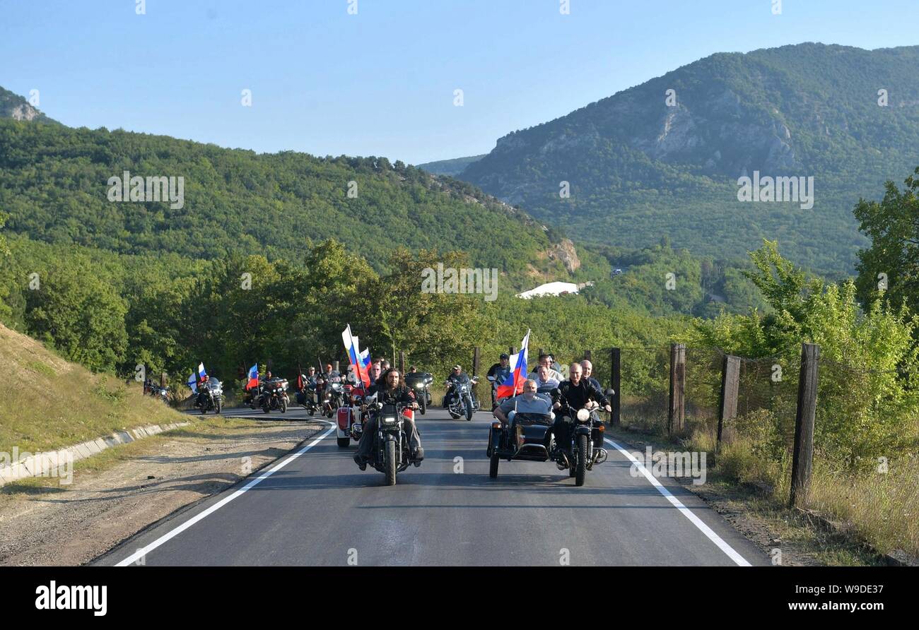 Russian President Vladimir Putin, right, rides a motorcycle alongside the Night Wolves biker gang leader Alexander ‘The Surgeon’ Zaldastanov, left, on their way to the Babylon Shadow bike show and camp August 10, 2019 near Sevastopol, Crimea, Russia. Riding behind Putin in pillion on the motorcycle is Acting Governor of Sevastopol Mikhail Razvozhayev and Head of the Republic of Crimea Sergei Aksyonov is in the sidecar. Stock Photo