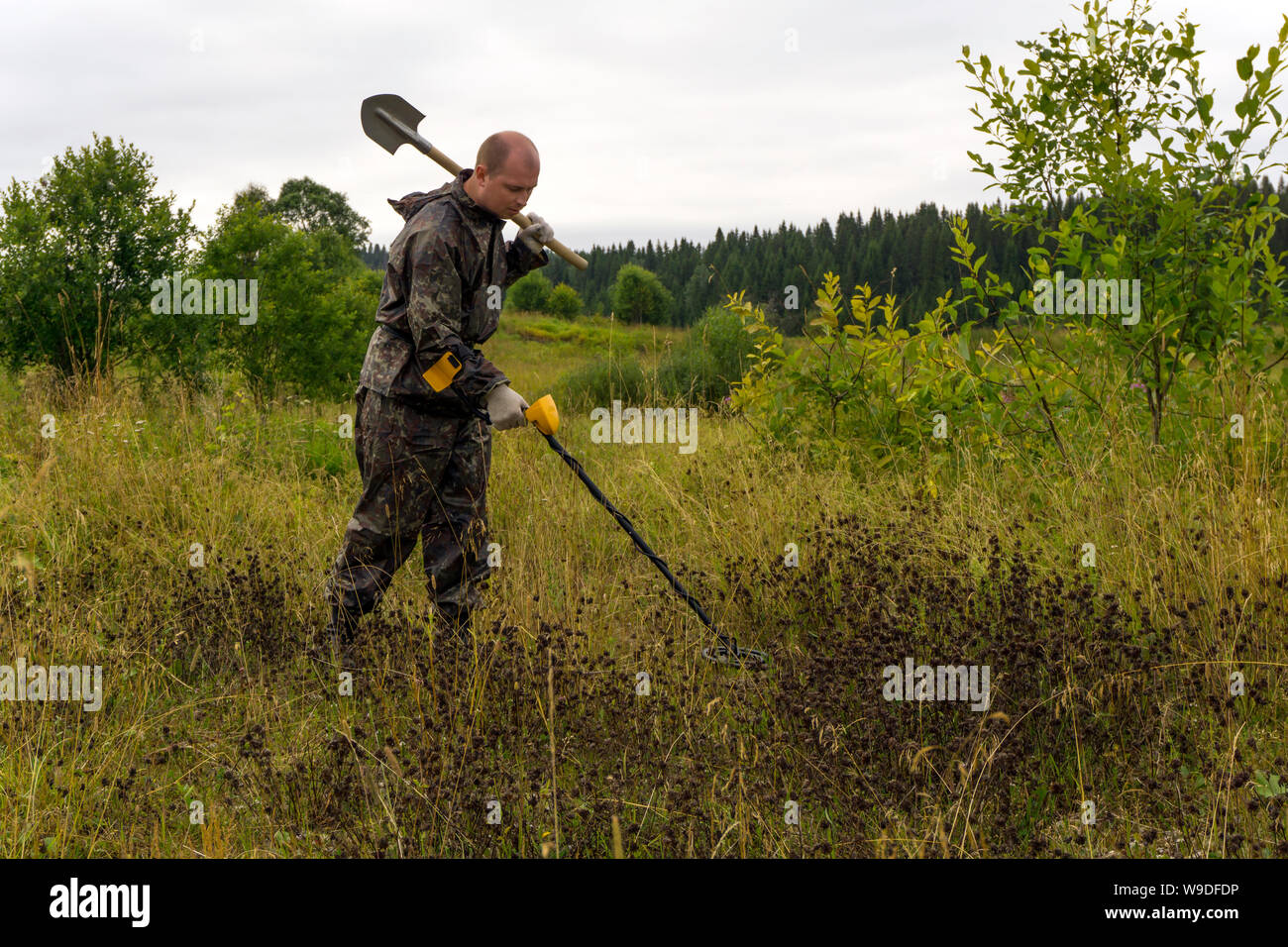 treasure hunter with a shovel and metal detector in a natural landscape ...