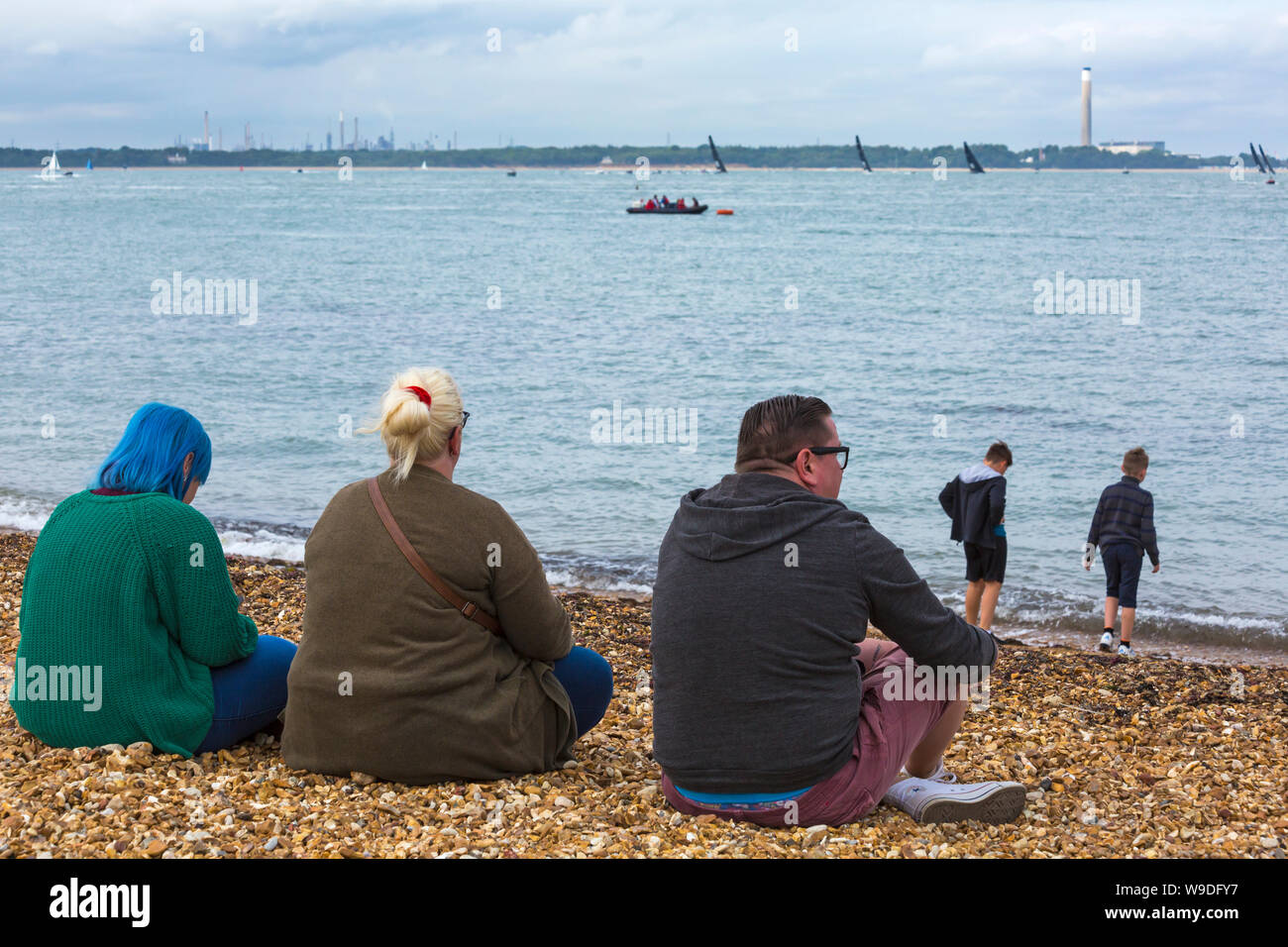 Spectators sitting on beach watching the sailing at Cowes, Isle of ...