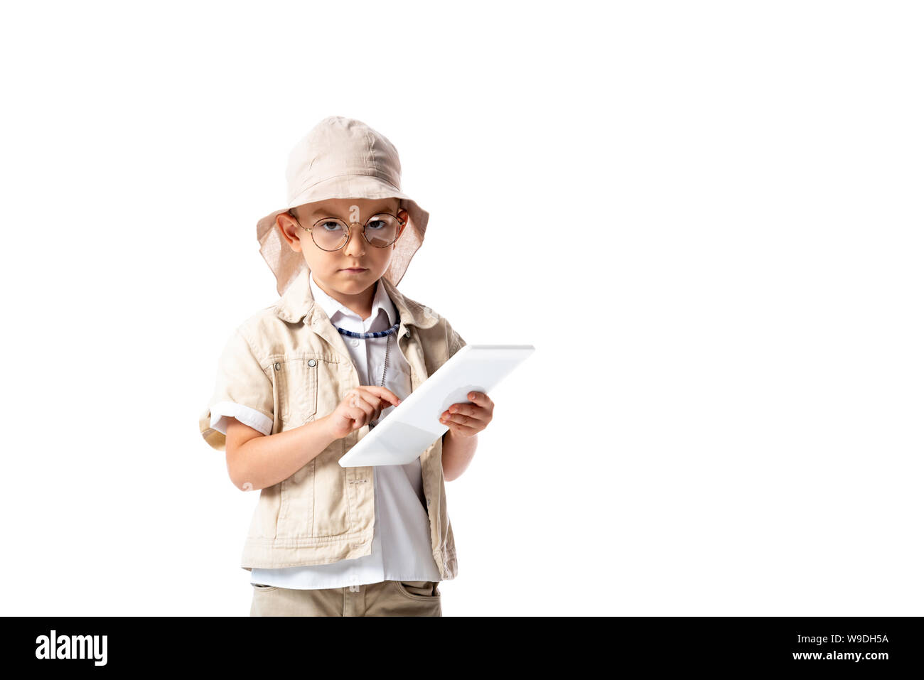 serious explorer child in glasses and hat holding digital tablet and looking at camera isolated on white Stock Photo