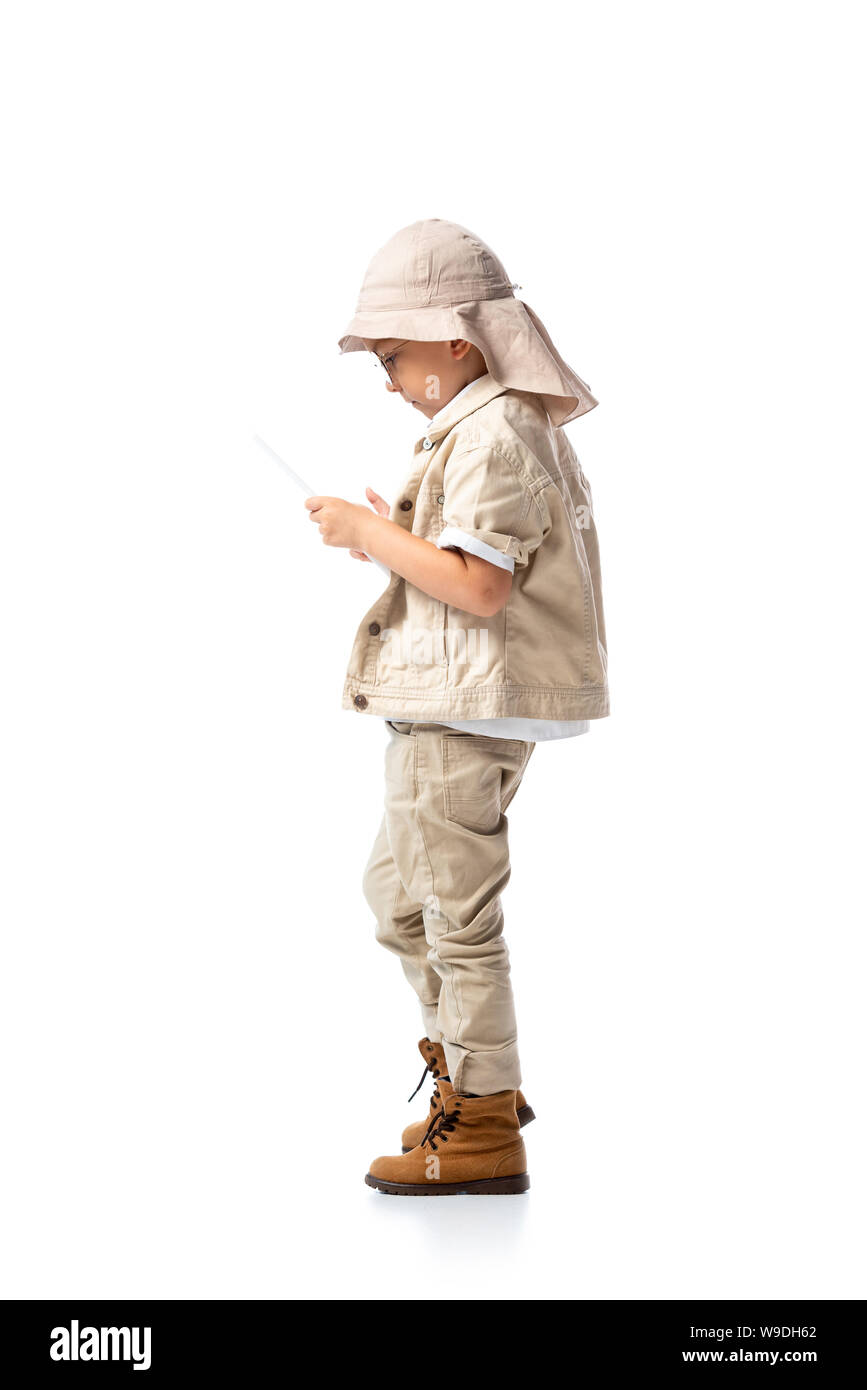 side view of explorer child in glasses and hat using digital tablet isolated on white Stock Photo