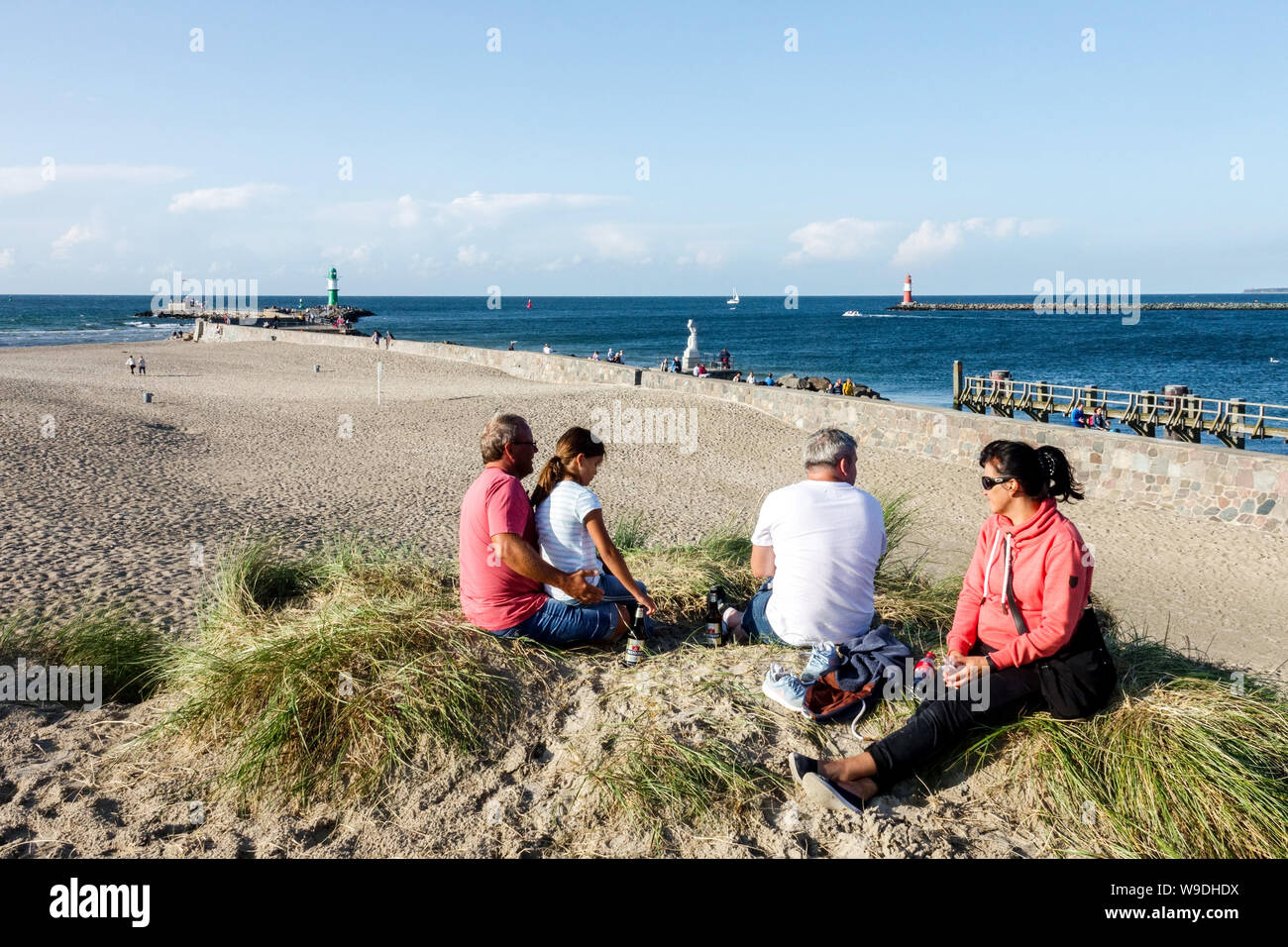 Family beach people enjoying a sunny day in the sand dunes overlooking the beach in Warnemunde dunes Germany Stock Photo