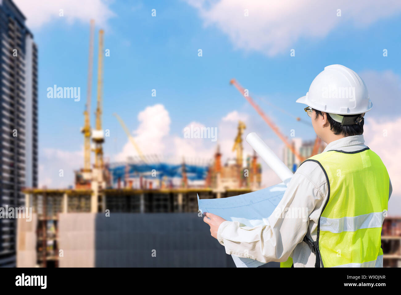 Construction engineer checking construction drawing at construction site of infrastructure project. Stock Photo