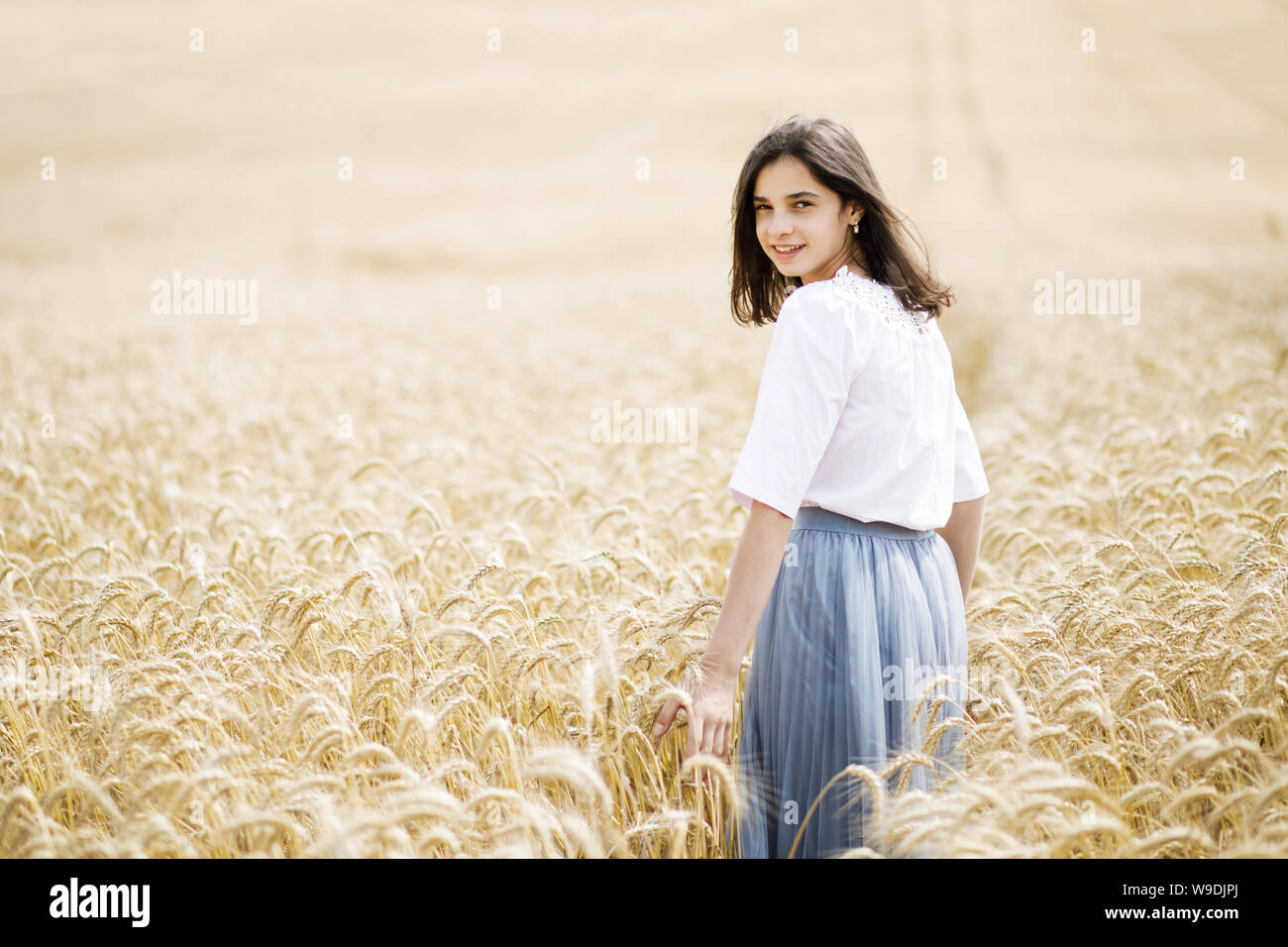 Beauty Girl Outdoors enjoying nature. Beautiful Teenage Model girl running on wheat field Stock Photo