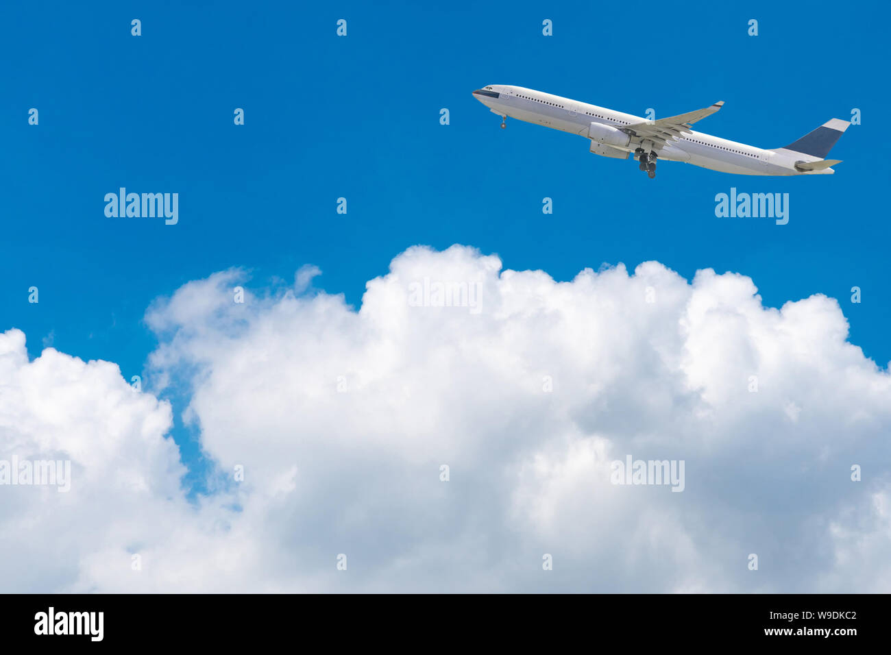 Commercial airplane flying over bright blue sky and white clouds. Elegant Design with copy space for travel concept. Stock Photo