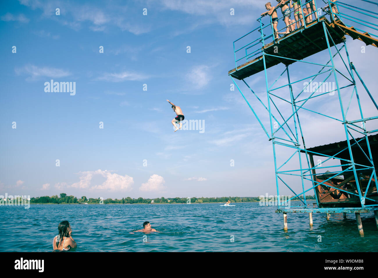 ZADOROZHNE, UKRAINE - July 28, 2019: people having fun at summer lake jumping from tower copy space Stock Photo